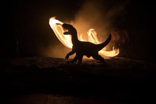巨大恐龙的剪影在黑暗的雾夜。有创意的小装饰。燃烧的模糊背景。图片下载