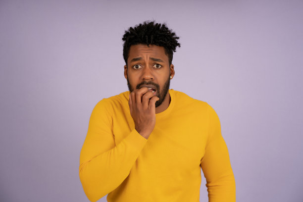 惊恐的男子一边看着摄像机，一边用手捂住自己的嘴。图片下载