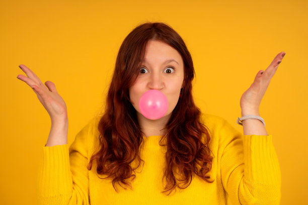 震惊的女人用口香糖做气球。图片下载