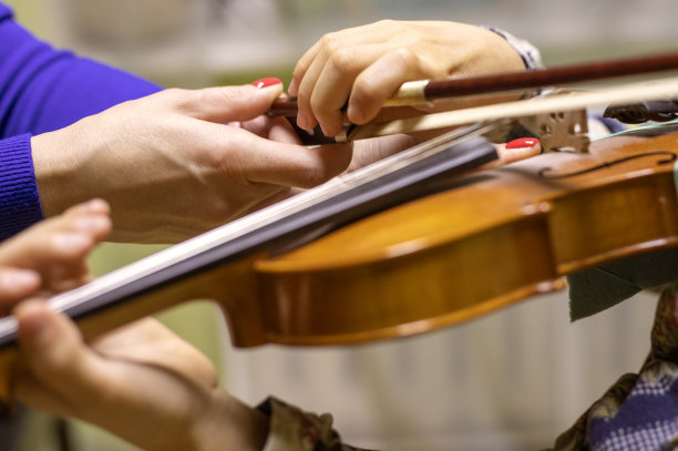 老师的手拉直年轻小提琴手的右手，年轻小提琴手在拉小提琴时抓住脖子，图片下载