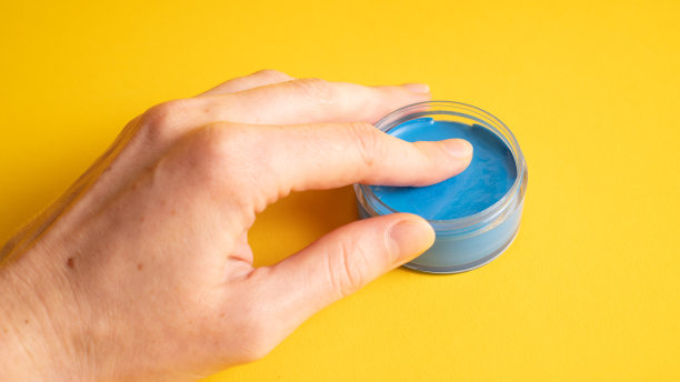 手里拿着万圣节蓝色化妆板。在透明的蓝色容器上涂上黄色图片下载
