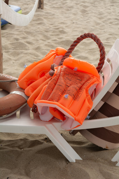 沙滩背景上的橙色救生衣和救生圈。海滩救生员的概念。图片下载