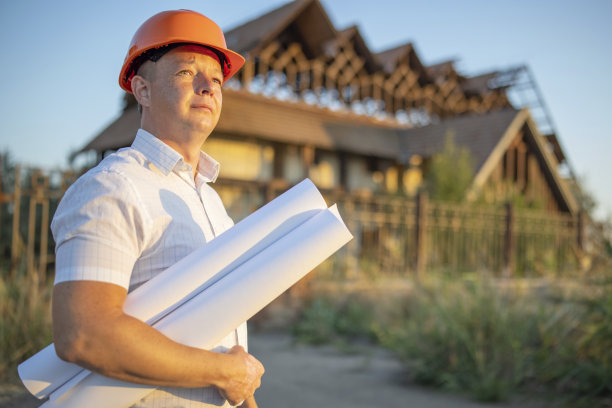 图为，在需要重建或维修的建筑物前的施工现场，戴着黄色头盔的年轻工程师。图片下载