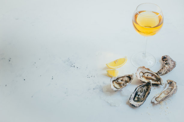 一杯白葡萄酒的特写，白色背景上有牡蛎和柠檬图片下载