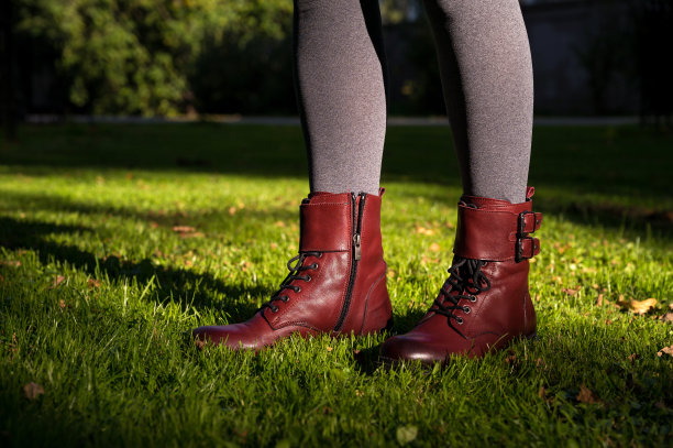 秋季女性时尚。草地上的腿的特写。勃艮第皮鞋。古典风格的靴子。灰色的紧身裤。阳光。图片下载