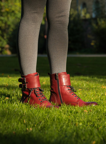 秋季女性时尚。草地上的腿的特写。勃艮第皮鞋。古典风格的靴子。灰色的紧身裤。阳光。图片下载