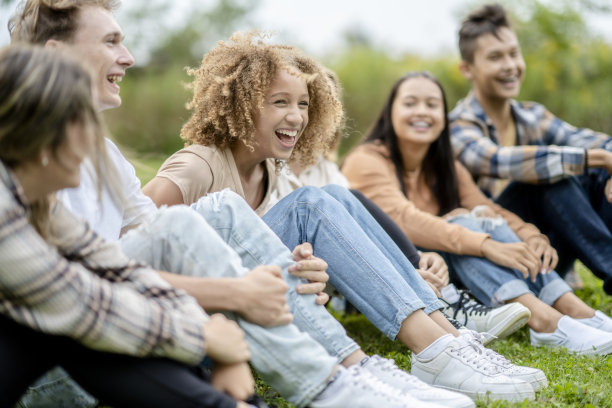 多民族高中学生坐在外面一起笑图片下载