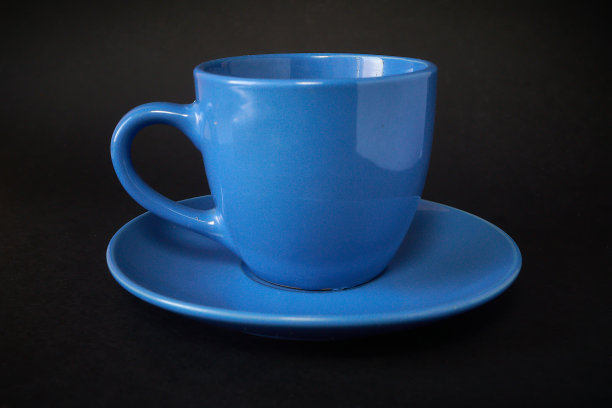 浅蓝色的咖啡杯和黑色背景的茶碟。图片下载