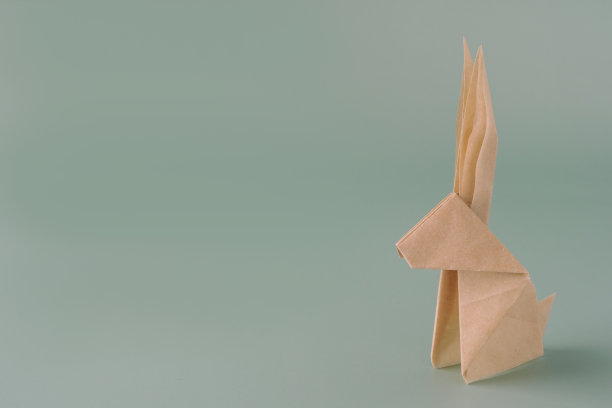 蓝色粉彩背景上的纸折纸兔子。纸做的工艺品。复活节或兔年的最小概念。复活节兔子，复制空间图片下载