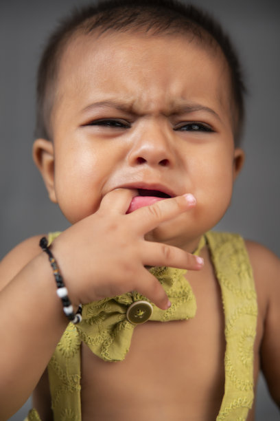 灰色背景下可爱的小女孩哭泣的特写。图片下载