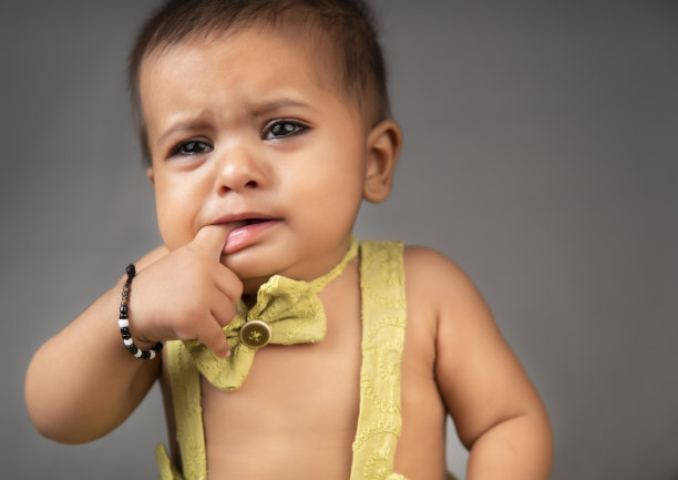 灰色背景下可爱的小女孩哭泣的特写。图片下载