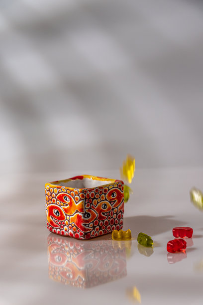 彩色瓷罐与帽上的白色背景反射和彩色糖果图片下载