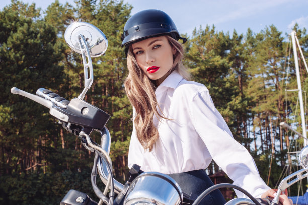 穿着白色衬衫和黑色头盔的金发女子骑着摩托车的图像图片下载