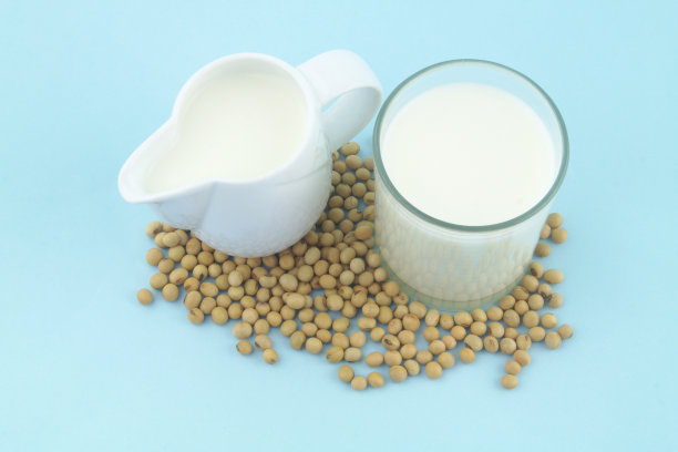 水罐和玻璃罐里的豆浆，蓝色背景上有大豆图片下载