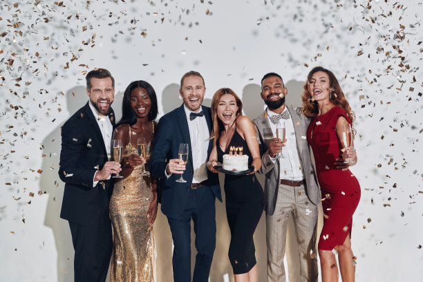 一群快乐美丽的人，穿着正装，手拿生日蛋糕和香槟酒杯图片下载