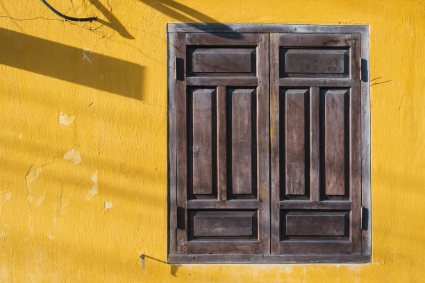 黄色古色古香的墙上有一扇棕色的窗户，带有复制空间图片下载