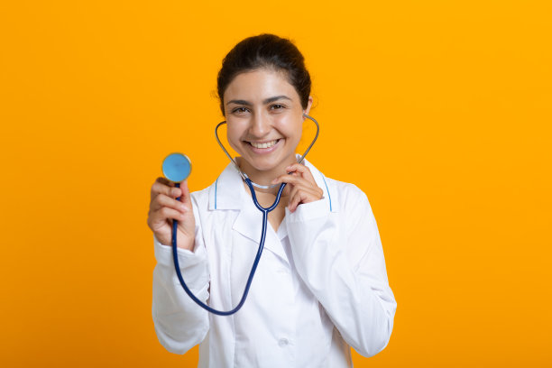 印度女医生的肖像，穿着白色的大褂孤立在黄色的背景图片下载