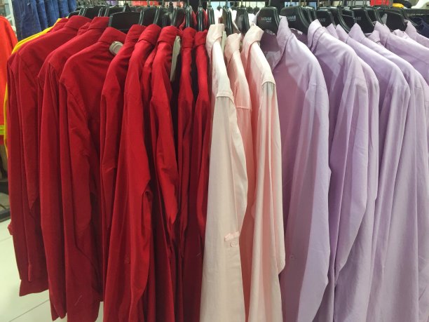 百货商店里的衬衫都挂在按颜色分类的衣架上。图片下载