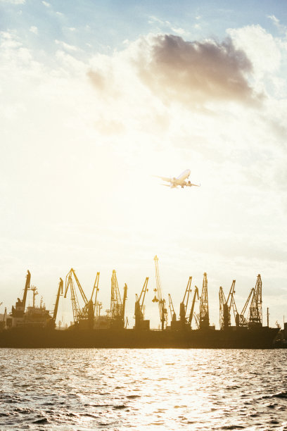 集装箱货轮和货机的物流运输与工作吊桥在港口的黄昏天空图片下载