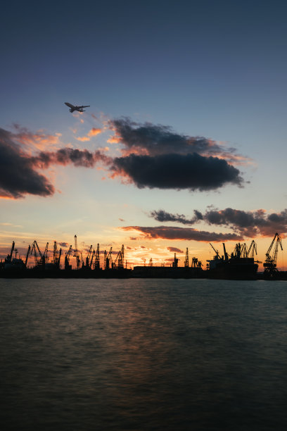 集装箱货轮和货机的物流运输与工作吊桥在港口的黄昏天空图片下载