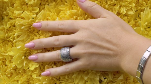 一位漂亮的女性手修得很好，手上戴着昂贵的戒指，手指在黄色的花瓣上划过图片下载