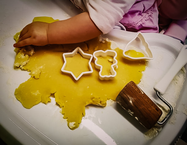 一个婴儿坐在高脚椅上揉面团准备做圣诞饼干图片下载