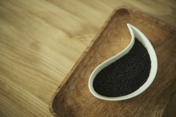 黑芝麻放在白盘子里。木制的桌子。软选择性模糊背景图片下载