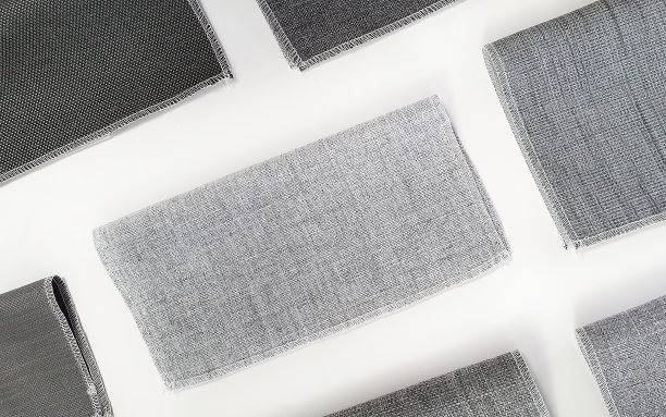 俯视图的多种灰色窗帘织物样品的室内材料选择。关闭窗帘材料显示刺绣细节。室内装饰样品在浅色背景上。图片下载