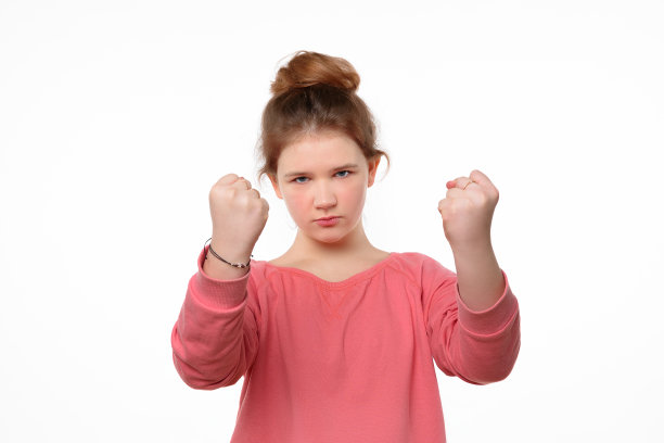 严厉的小女孩挥舞着拳头，看着镜头。人类情感，面部表情的概念图片下载