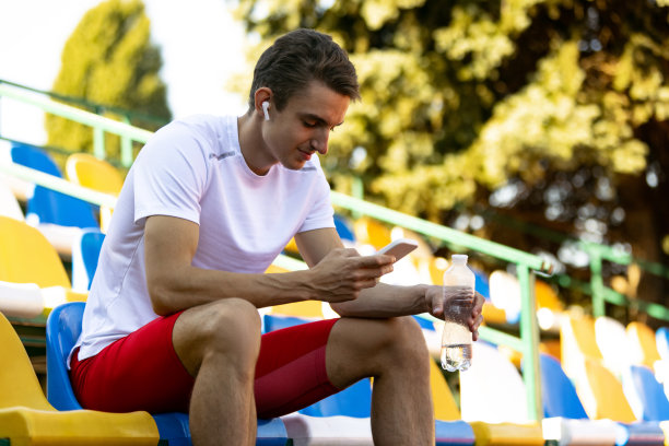 年轻白人男子的肖像，男性运动员，在公共体育场，运动场或户外跑道孤立的跑步者。夏天的运动游戏。图片下载