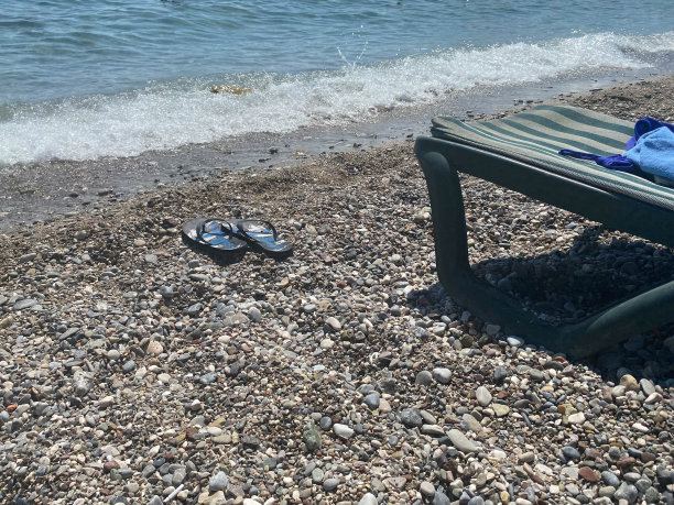 蓝色的人字拖在卵石滩上。夏天海滩主题图片下载