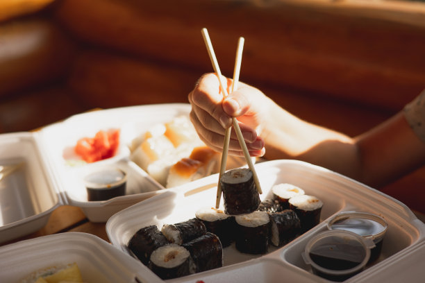 外卖寿司卷装在塑料食品容器中。日本料理。一套寿司卷在一次性容器。外卖服务和外卖概念图片下载