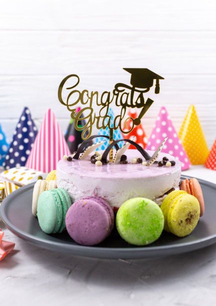 紫罗兰色的生日蛋糕，上面有花饰，祝贺毕业生，纸帽子，桌上有杏仁饼干。毕业晚会装饰图片下载