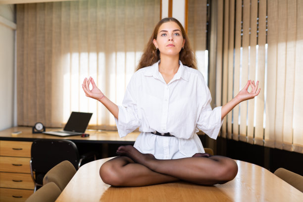 女簿记员在办公室的桌子上练习莲花姿势图片下载