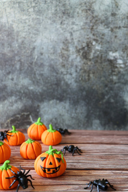 图片批自制，南瓜万圣节杰克灯设计橙色fondant糖霜食品着色面和绿色茎，蜘蛛，木材表面，斑点黑色背景，重点前景，复制空间图片下载