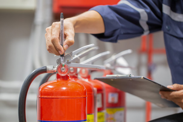 工程师正在检查消防控制室的灭火器罐，进行安全培训和防火。图片下载