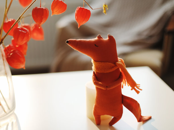 秋天的静物与一只玩具狐狸，鲜花，红色的酸浆树枝在一个花瓶在一个舒适的家内部图片下载