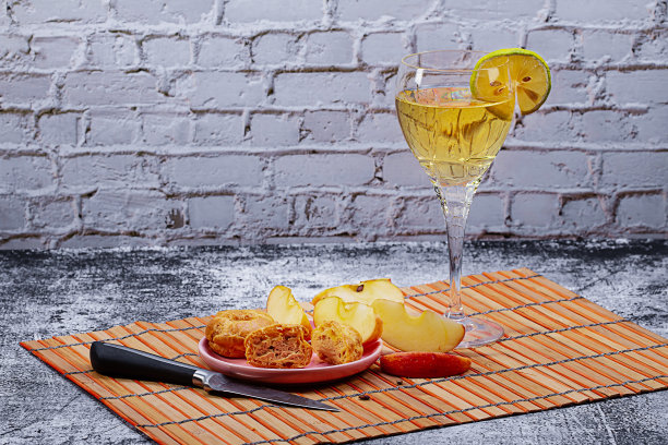 一杯柠檬葡萄酒、一份闪电泡芙和厨房桌上的苹果片美食照片图片下载