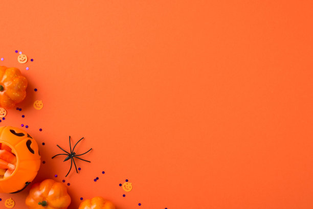 万圣节装饰南瓜篮与糖果玉米蜘蛛和紫罗兰亮片在孤立的橙色背景与copyspace的顶部视图照片图片下载