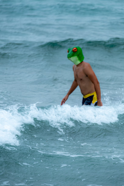 一个戴着青蛙面具的年轻人在大海和海浪中游泳图片下载