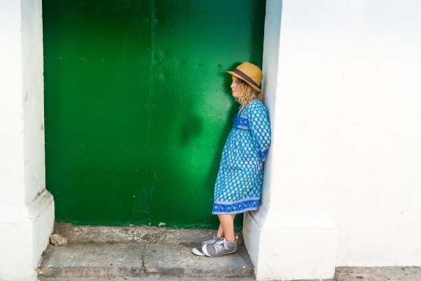 一个可爱的年轻女孩戴着软呢帽站在门口，古怪的肖像图片下载