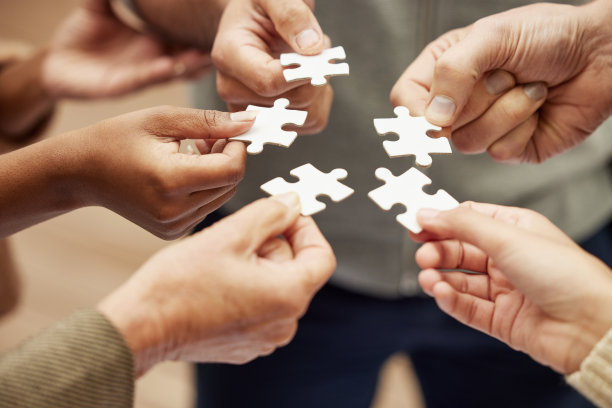 特写镜头是一群不认识的人把拼图拼在一起图片下载