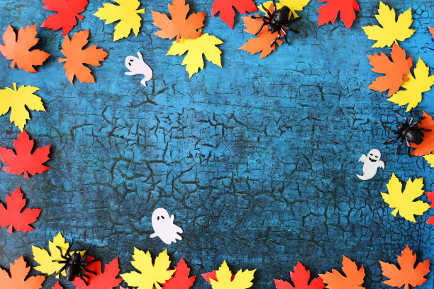 秋天的形象，万圣节设计海报框架，自制剪影剪纸形状的秋天彩色叶子，红色，橙色和黄色枫叶和鬼魂形状的边界，蜘蛛在裂纹的蓝色背景，秋天万圣节墙纸背景，副本图片下载
