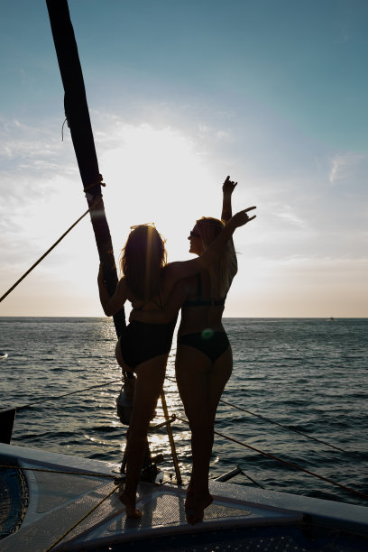 日落时分，两个年轻女子在公海上的一艘游艇上休息图片下载