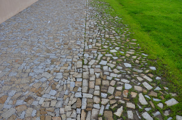 铺装路面与草坪之间的过渡。草坪生长在一块块随机放置的花岗岩碎块铺路石之间。饱满到非常松散的纹理图片下载