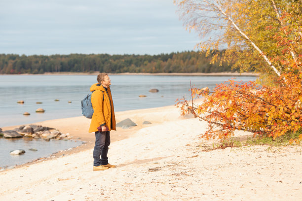 一个白种人站在湖边欣赏风景。走了很长一段路的人在休息图片下载