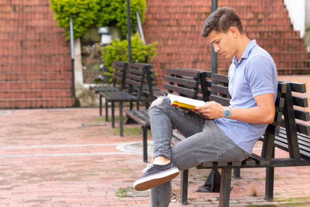 年轻的成年人在砖砌的公园里阅读。一个人在一个安静放松的地方。图片下载
