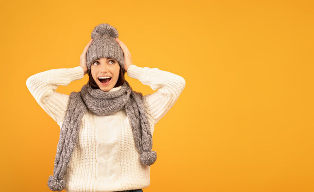 这是难以置信的。惊讶的年轻女士穿着暖和的毛衣和针织套装，震惊地看到销售，黄色的背景图片下载