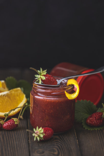 自制的草莓酱或橘子酱，玻璃瓶里放橘子，木桌上放成熟的草莓图片下载