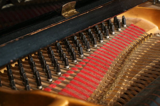 一个三角钢琴内部的细节，带有弦的别针或钉子和一些灰尘在旧的声学乐器，音乐和文化的概念，选定的焦点图片下载